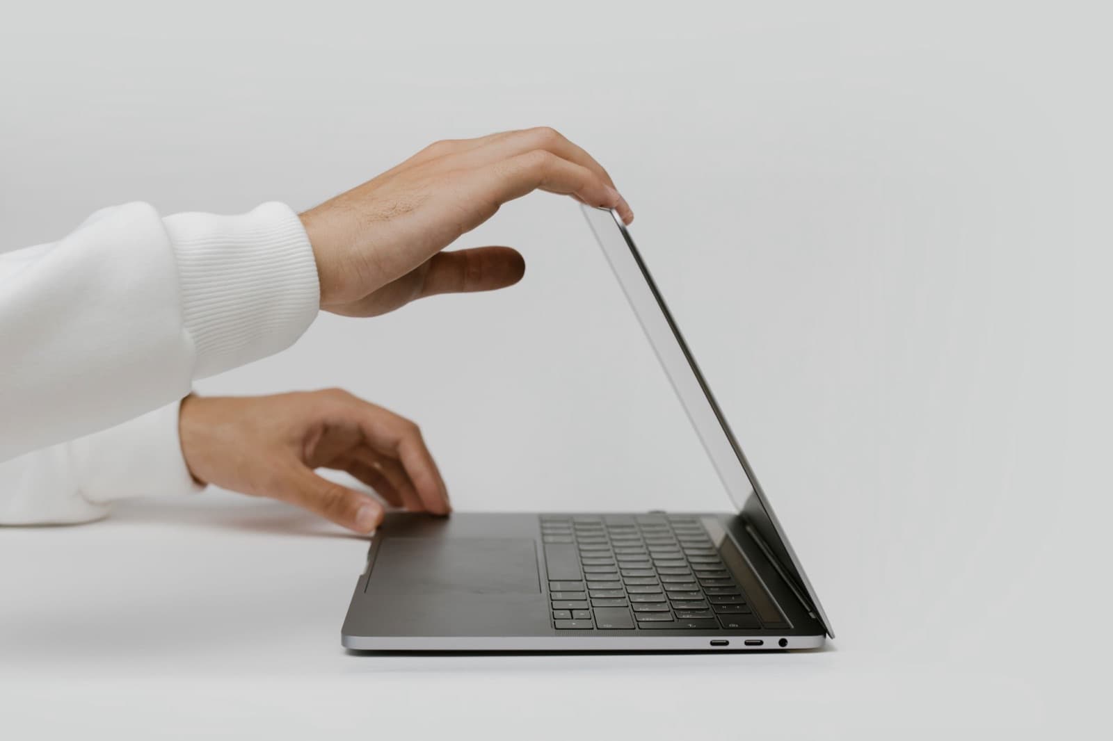 Une main ouvre l’écran d’un ordinateur portable